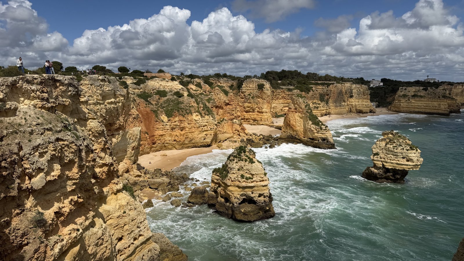 A panoramic view of layered coastal cliffs reaching out into a calm sea.