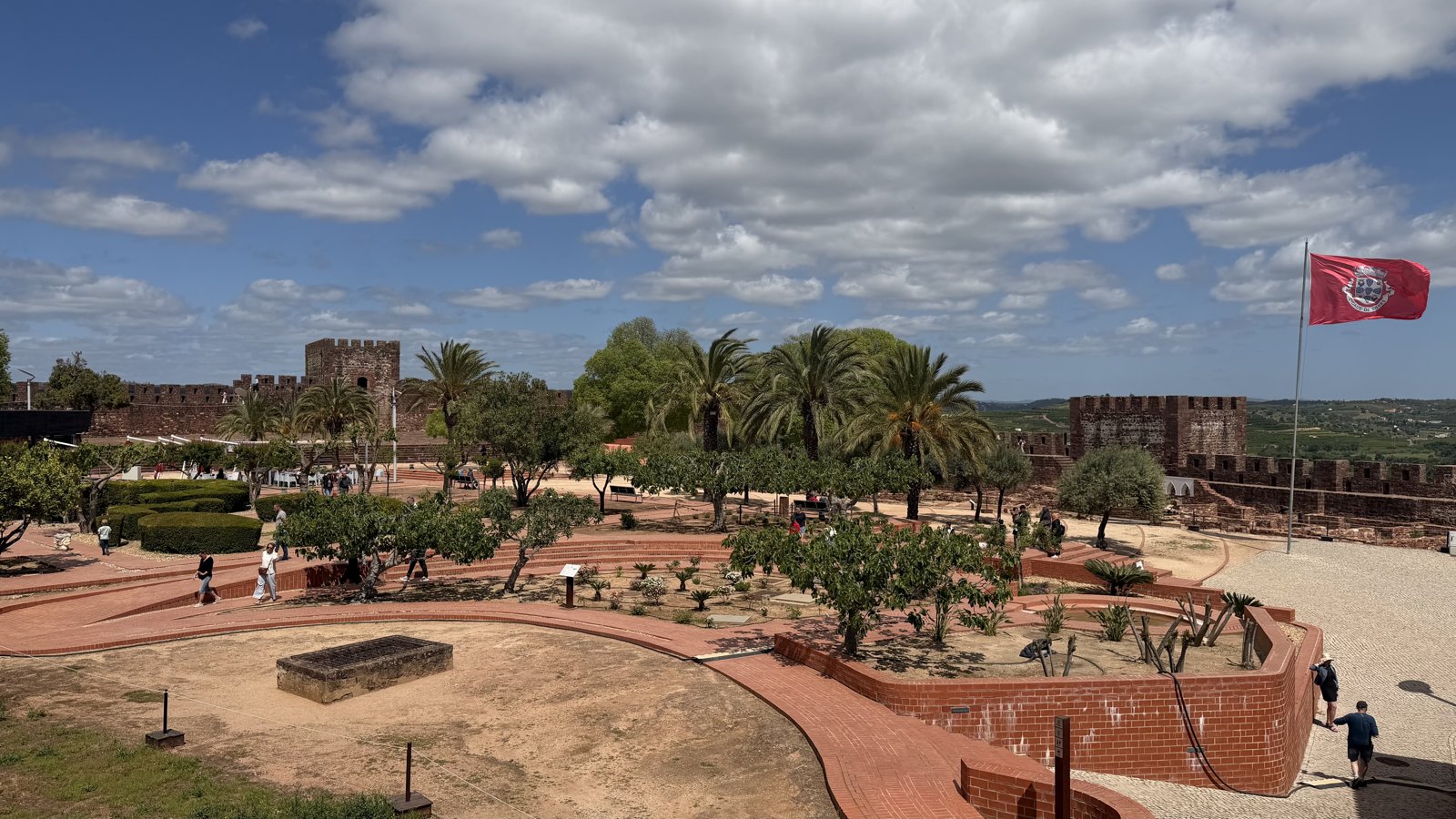 Curving red-brick pathways winding through the open courtyard of an old castle.