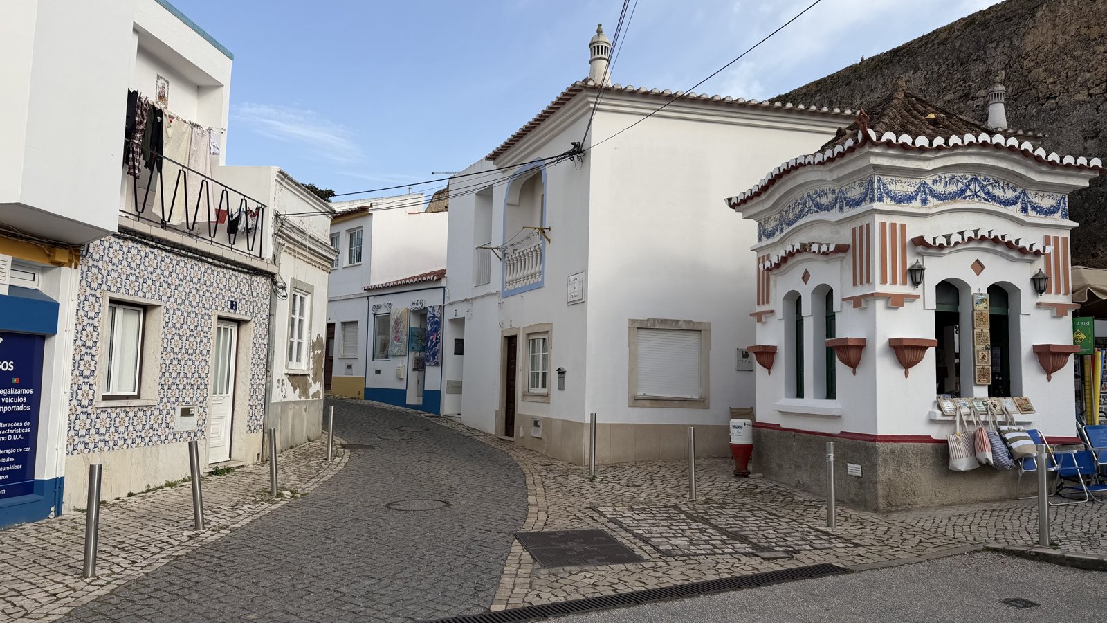 A narrow cobblestone street curving between traditional whitewashed houses.